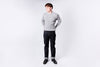 Man wearing a gray sweater and dark jeans on a white background