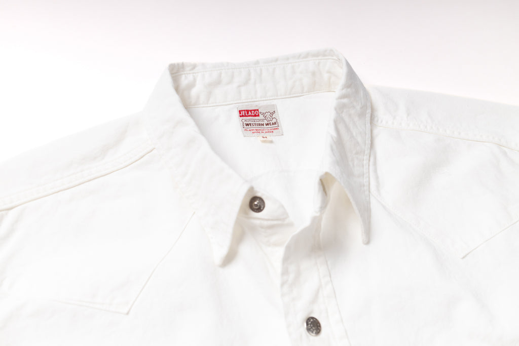 Close-up of a white cotton button-down shirt collar with a visible British Airways neck label and dark metal buttons.