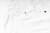 Close-up of a white denim garment showing a front chest pocket with a silver-toned button and part of a dark button on the right side.
