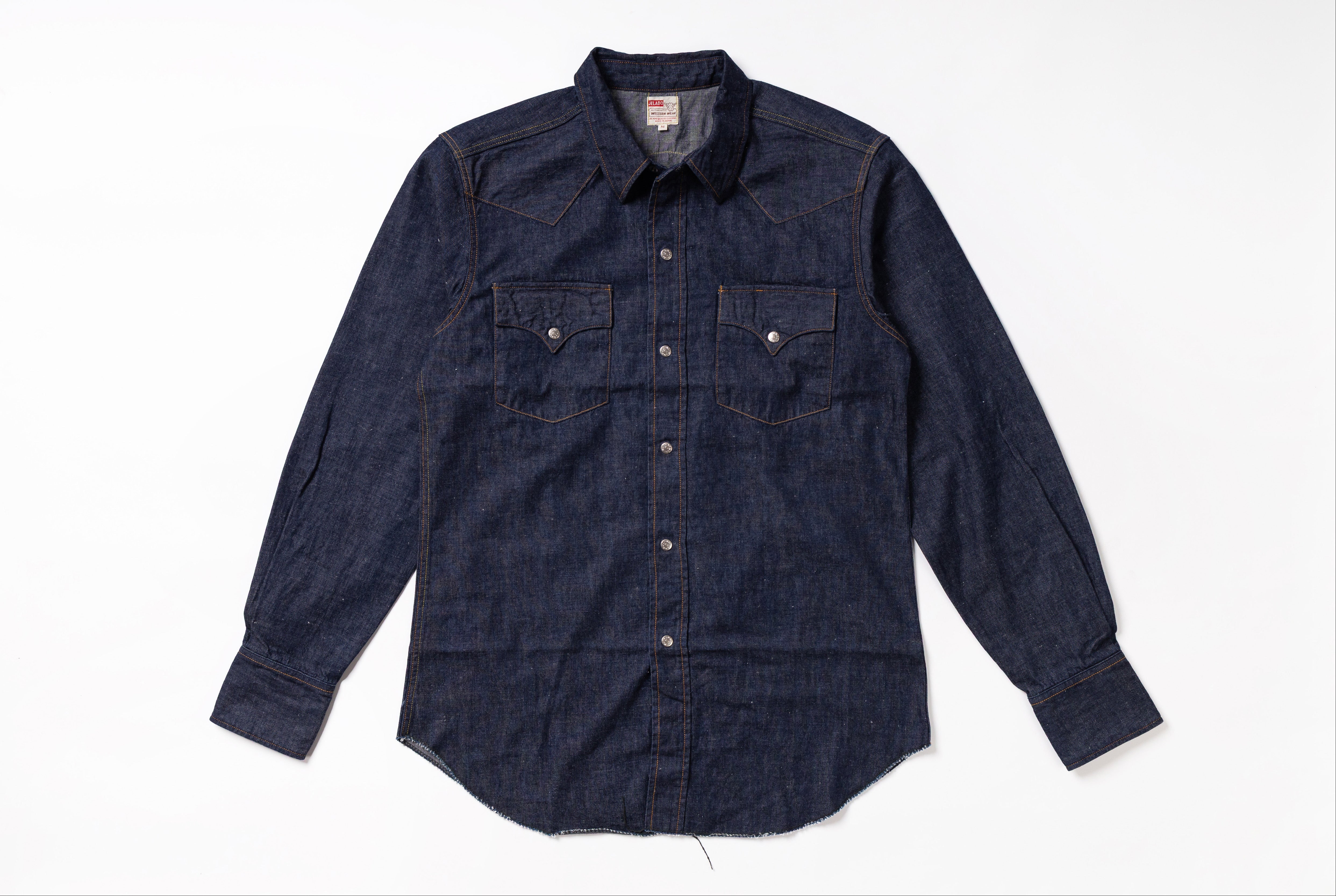 A dark indigo denim western-style shirt jacket with two buttoned chest pockets, laid flat on a white background.