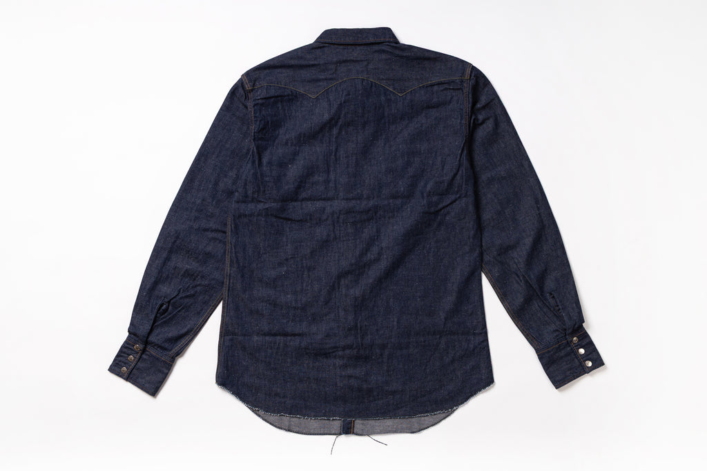A dark indigo denim long-sleeve shirt shown from the back, laid flat on a white background.