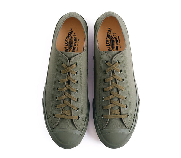 A pair of low-top canvas sneakers in olive green with matching green laces, shown from a top-down view on a white background. 