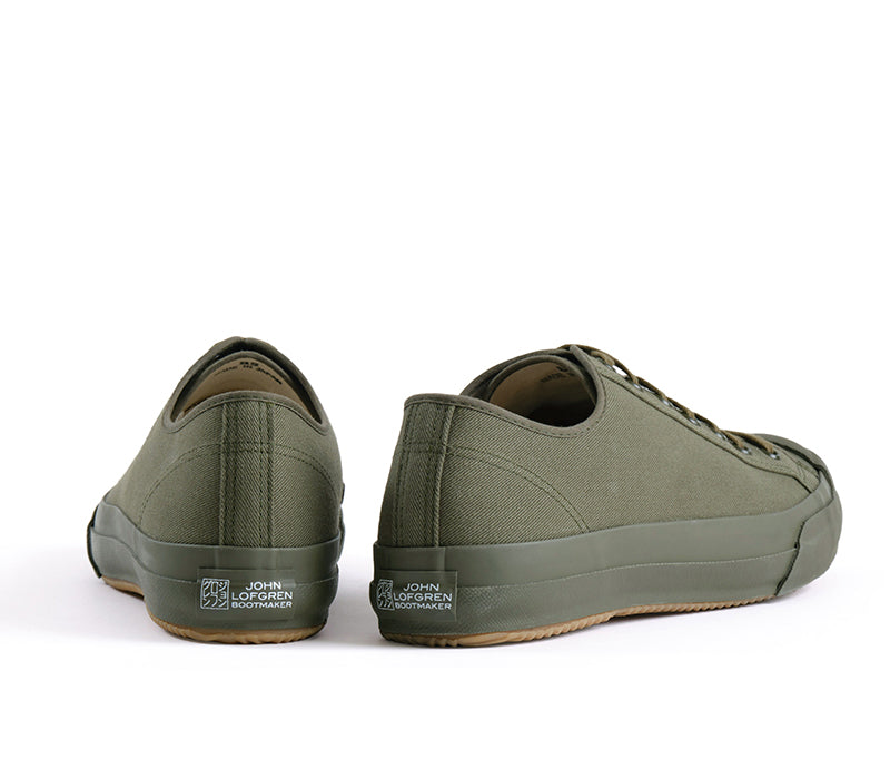 A pair of low-top canvas sneakers in olive green, shown from the rear three-quarter view on a clean white background. The brand 'John Lofgrenn' is visible on the heel.