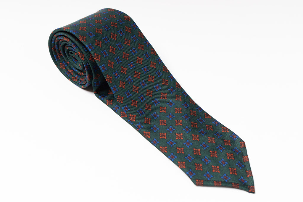 Folded green tie with red and blue pattern on a white background