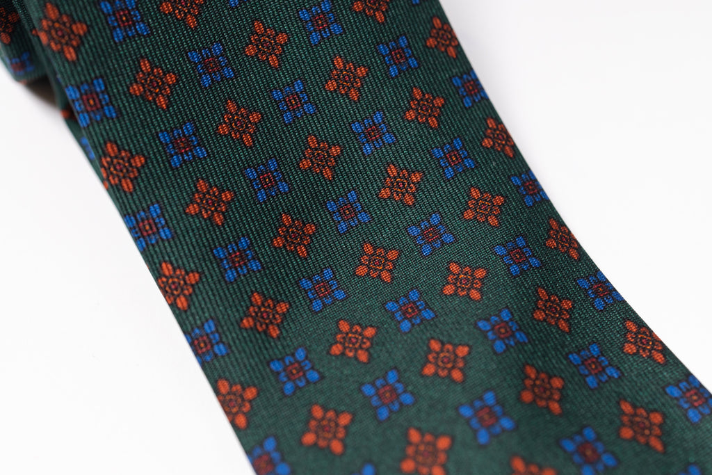 Green tie with red and blue geometric pattern on a white background