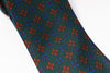 Green tie with red and blue geometric pattern on a white background