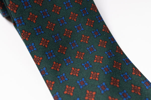 Green tie with red and blue geometric pattern on a white background