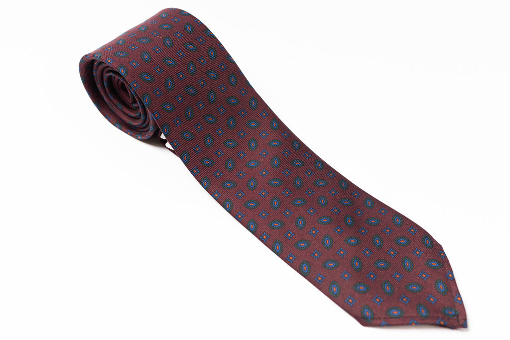 Maroon tie with blue pattern on a white background