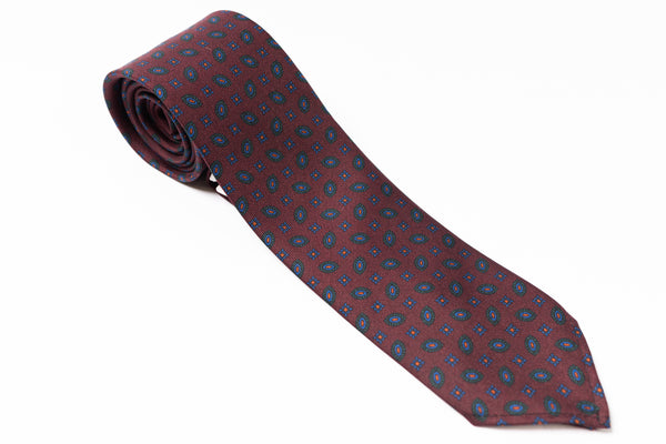Maroon tie with blue pattern on a white background