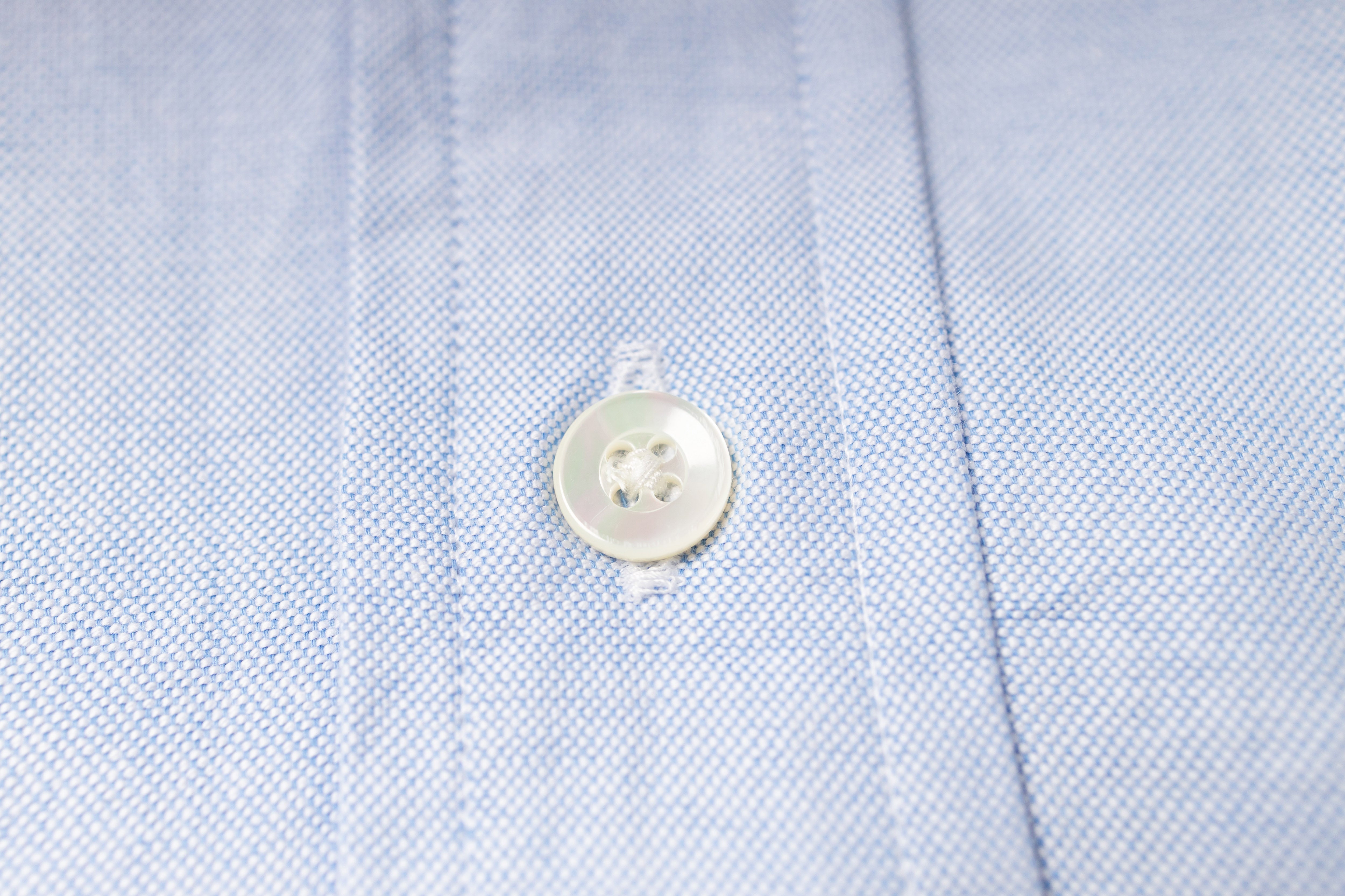 Close-up of a button on an blue fabric shirt