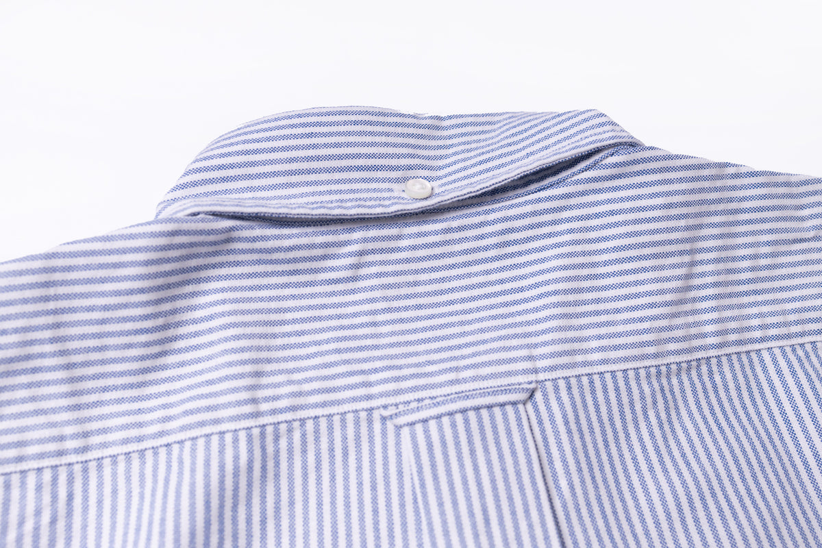Close-up of a blue and white striped button-down shirt collar with a single white button, set against a plain white background.