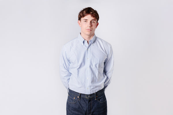 A man wearing a blue stripe oxford shirt on a white background