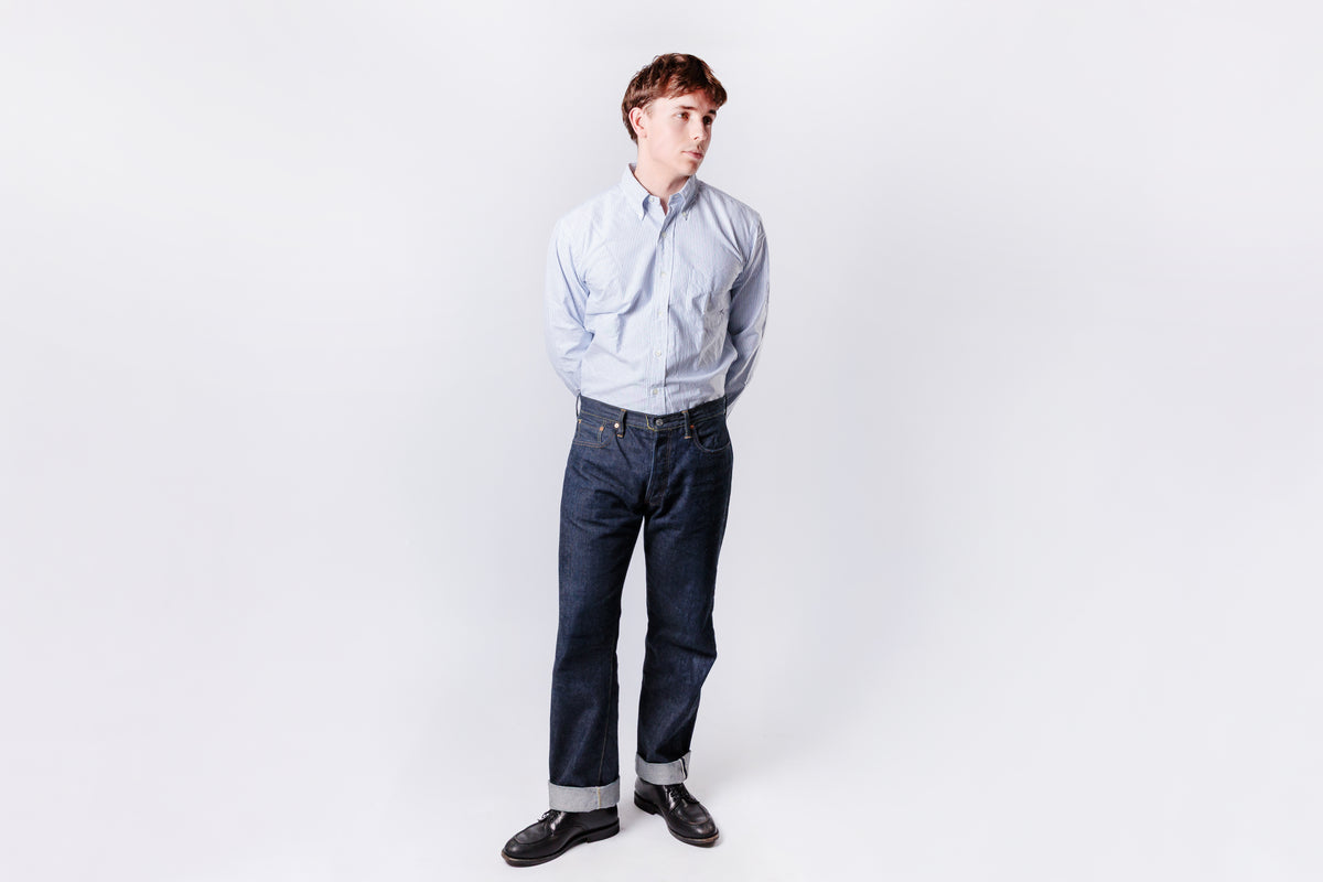 Person wearing a light blue shirt and dark jeans on a white background