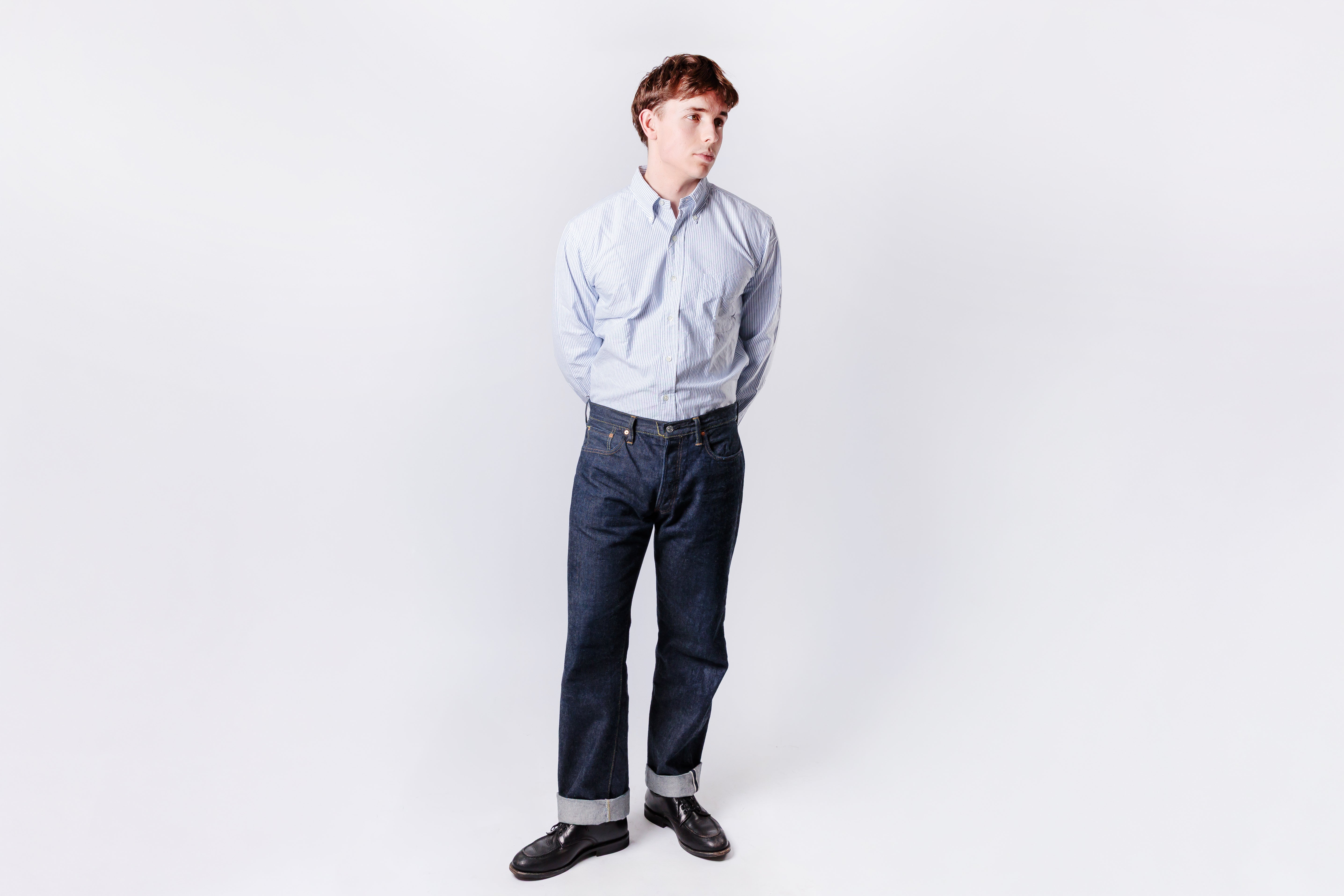 Person wearing a light blue shirt and dark jeans on a white background