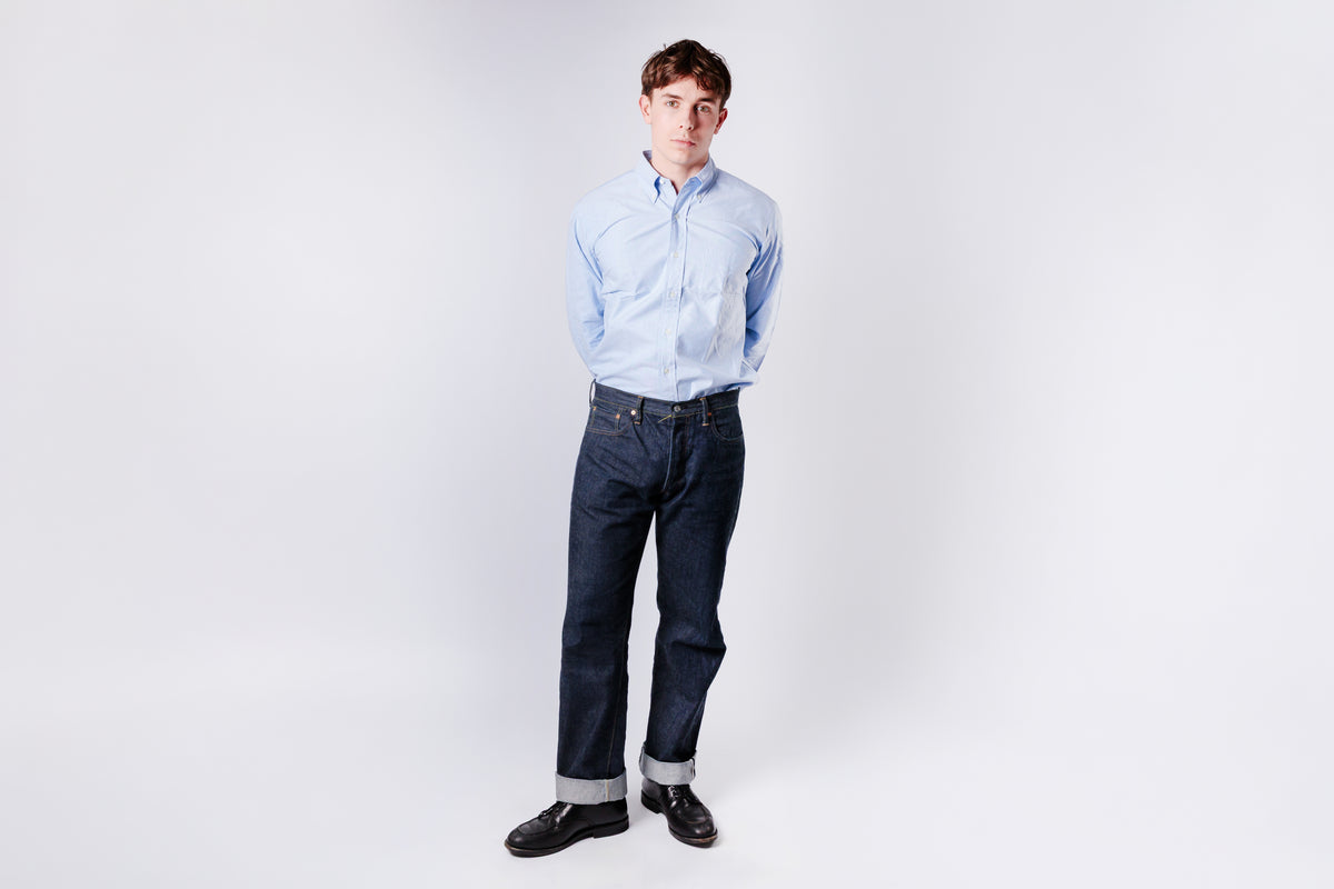 Person wearing an blue shirt and dark jeans on a white background