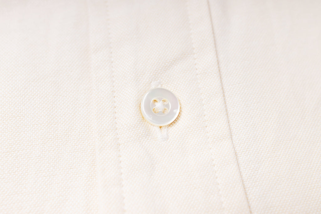 Close-up of a button on an ecru fabric shirt
