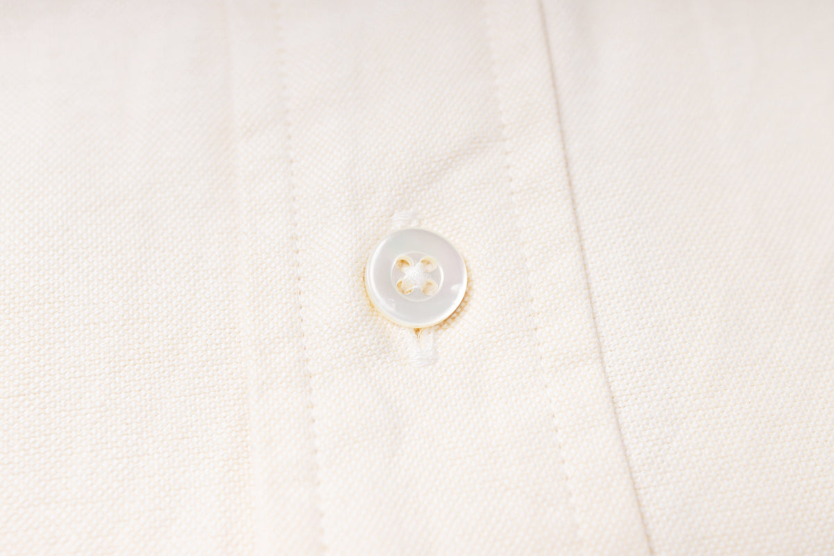 Close-up of a button on an ecru fabric shirt