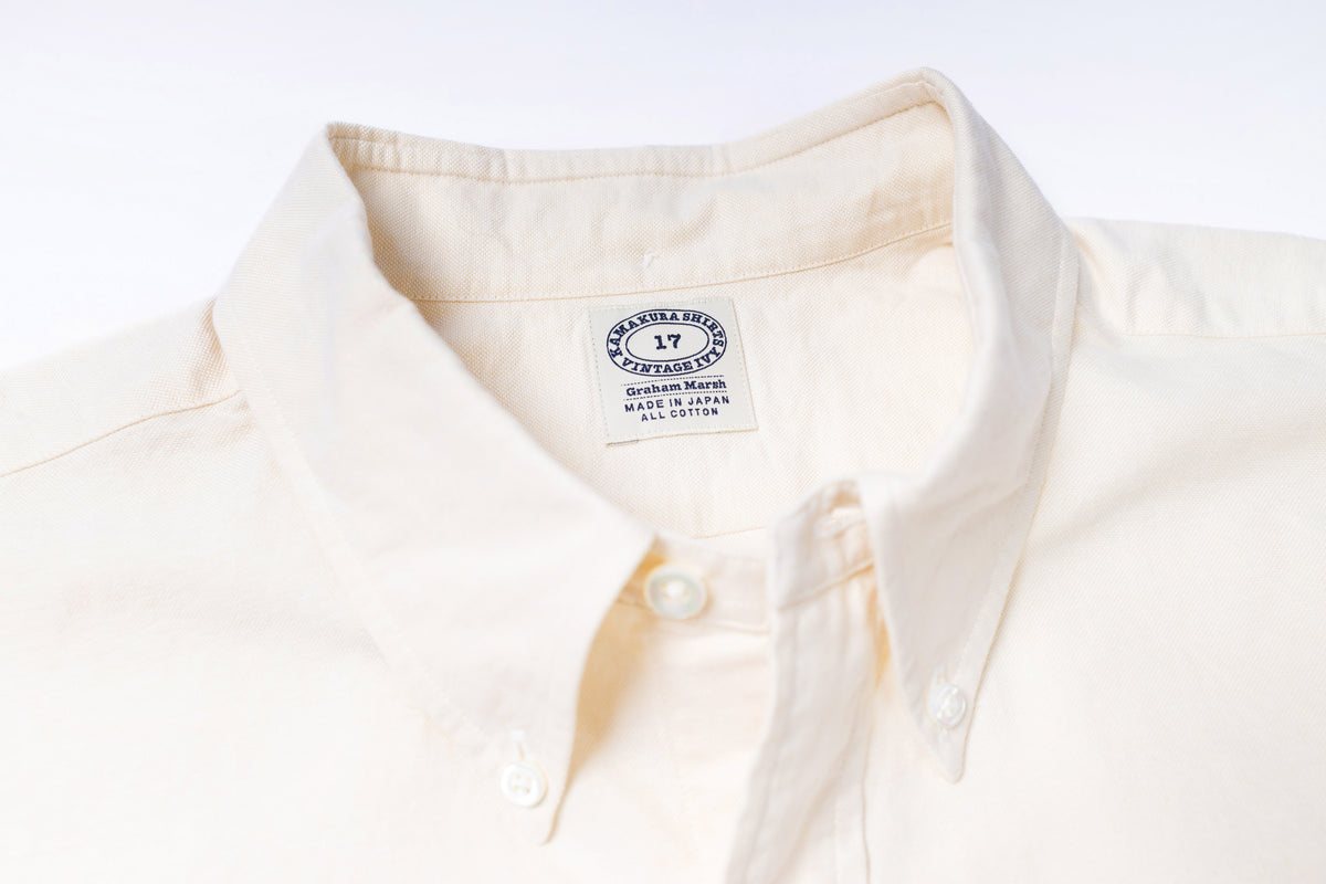 Close-up of a ecru shirt with a visible label on a light gray background