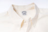 Close-up of a ecru shirt with a visible label on a light gray background