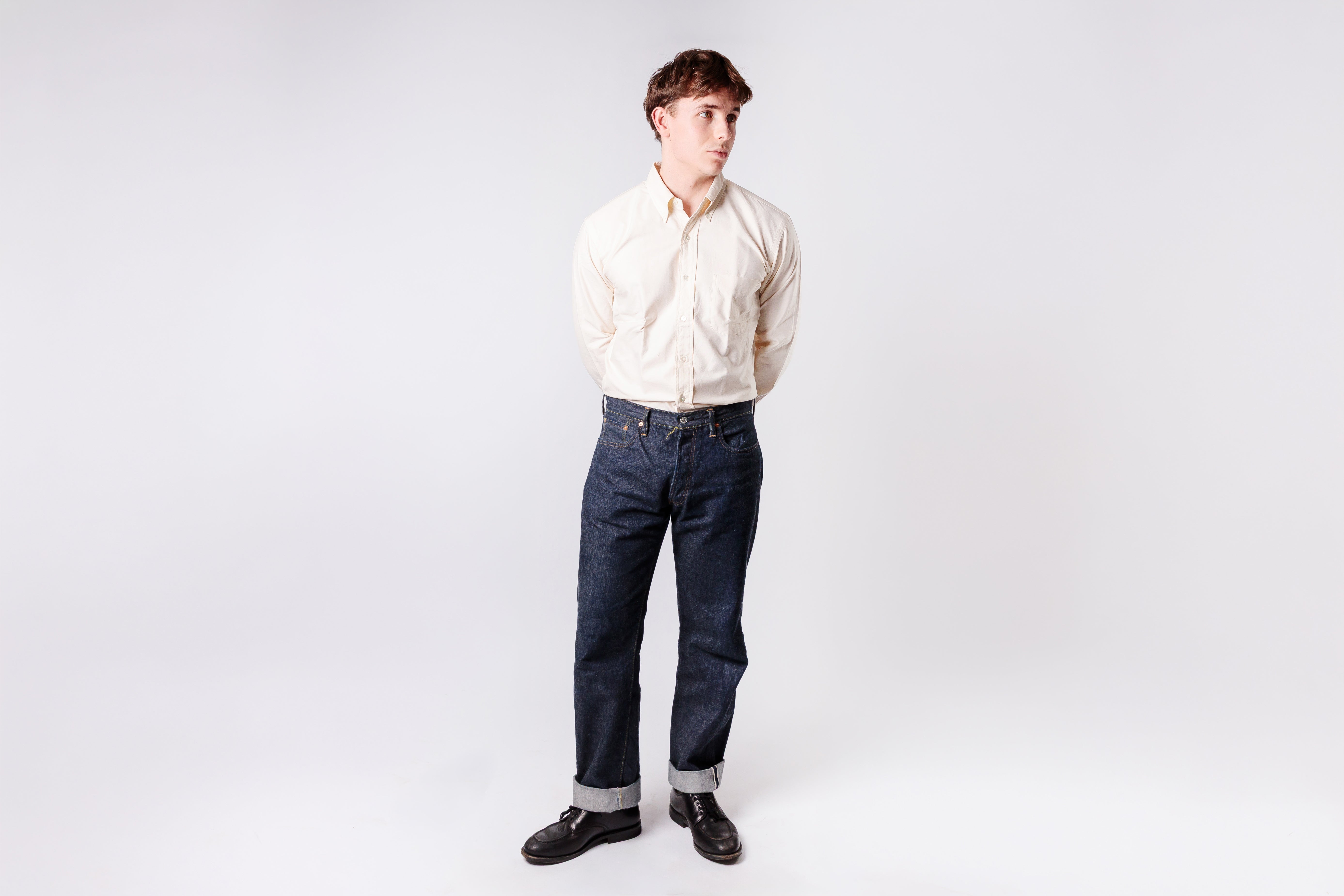 Person wearing an ecru shirt and dark jeans on a white background