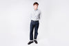 Person wearing a light blue shirt and dark jeans on a white background