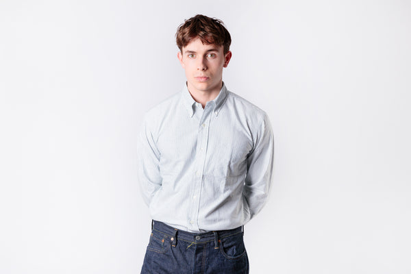 A man wearing a green stripe oxford shirt on a white background