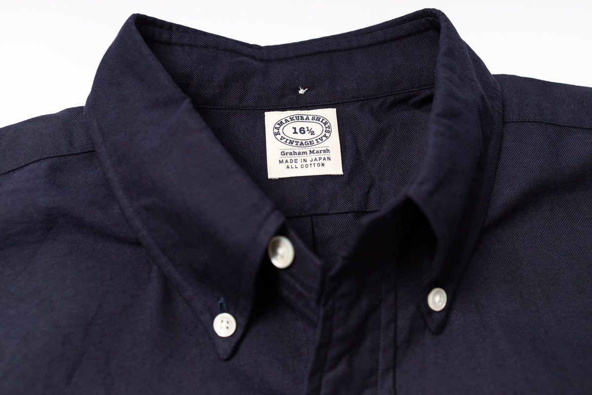 Close-up of a navy shirt with a visible label on a light gray background