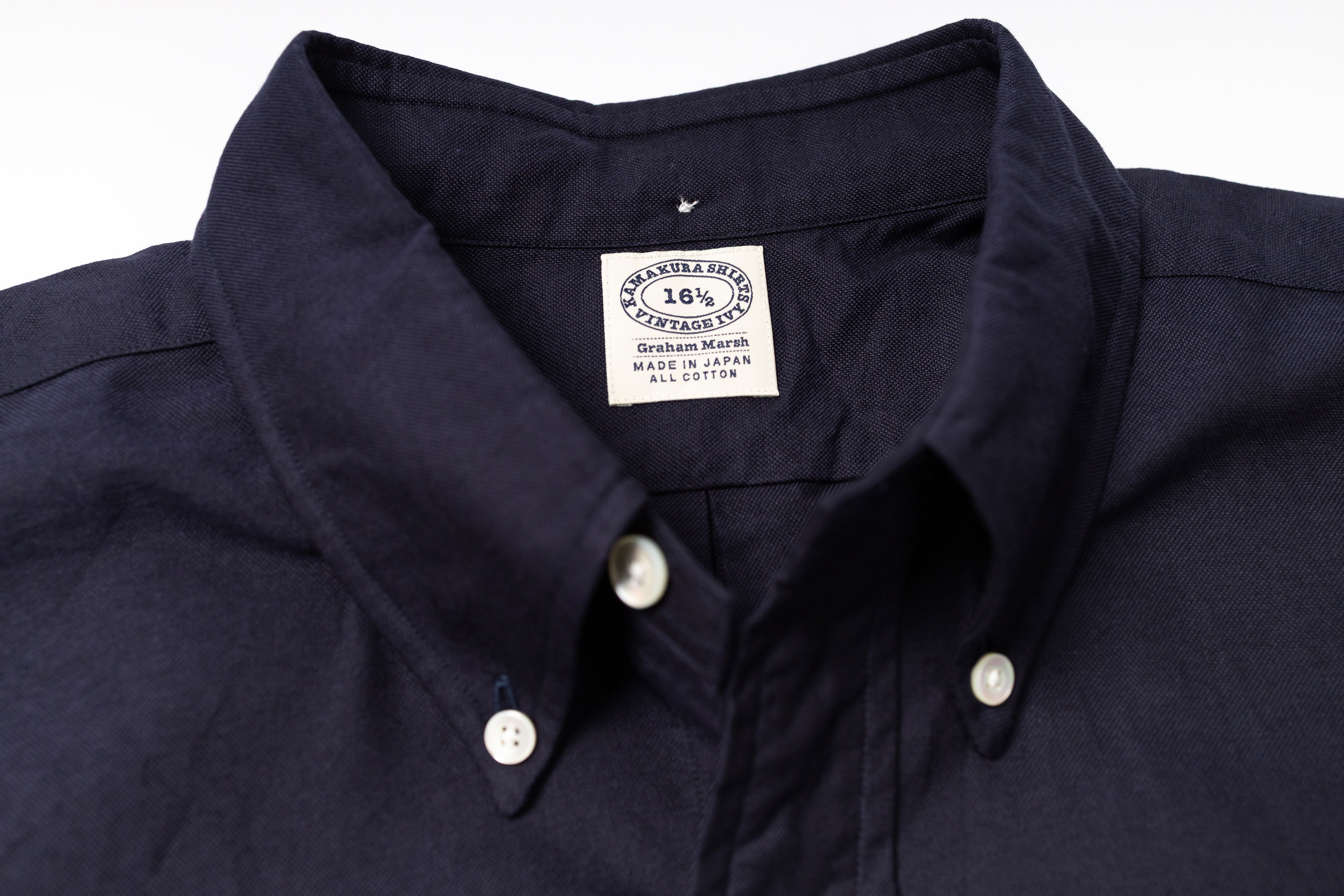 Close-up of a navy shirt with a visible label on a light gray background