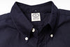 Close-up of a navy shirt with a visible label on a light gray background