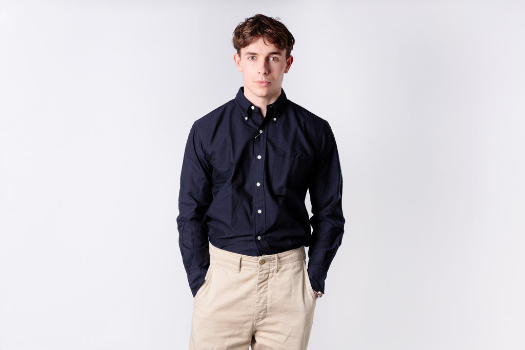 Person wearing an navy shirt and dark jeans on a white background