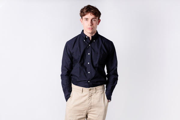 Person wearing an navy shirt and dark jeans on a white background
