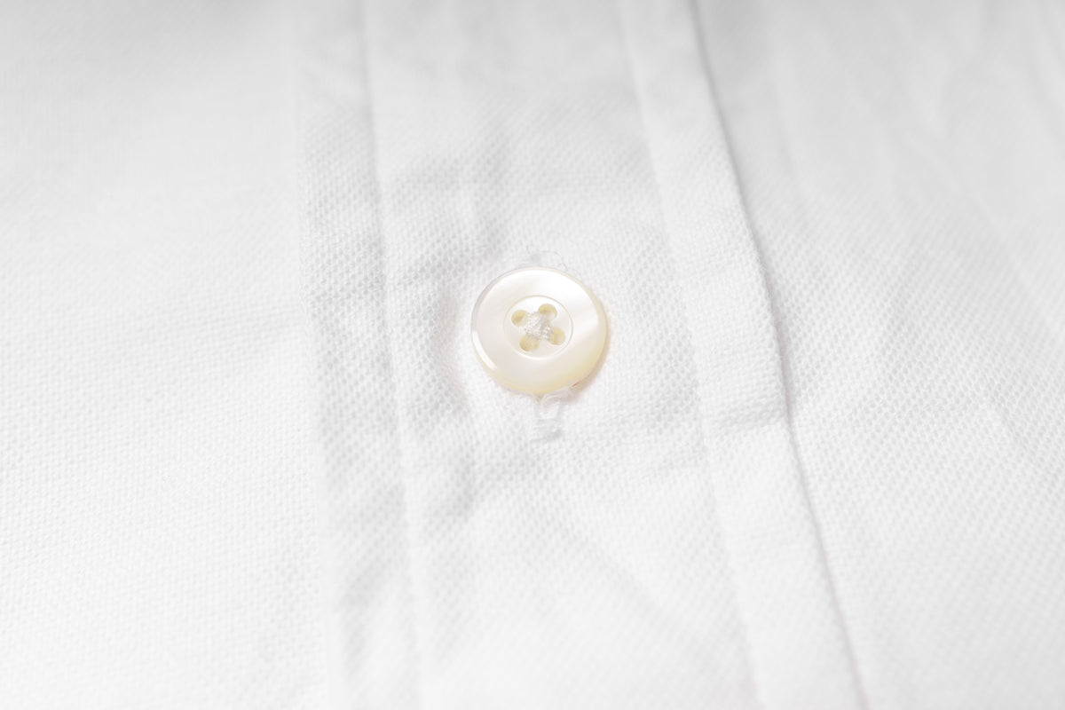 Close-up of a button on an white fabric shirt