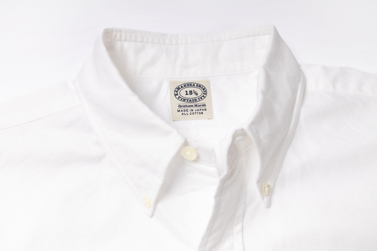 Close-up of a white shirt with a visible label on a light gray background