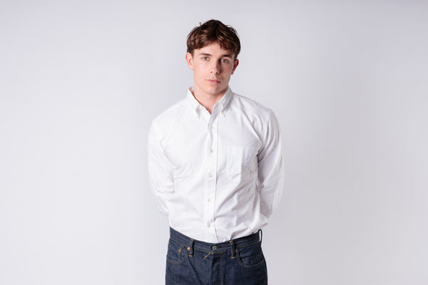 A man wearing a white oxford shirt on a white background