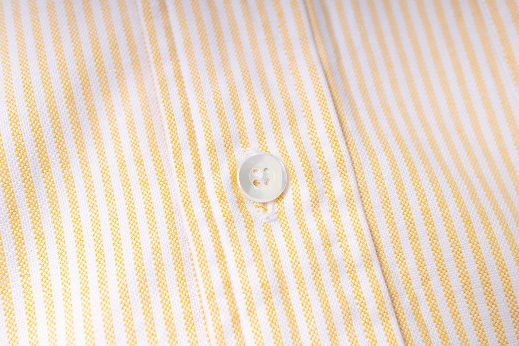 Close-up of a button on a striped fabric shirt