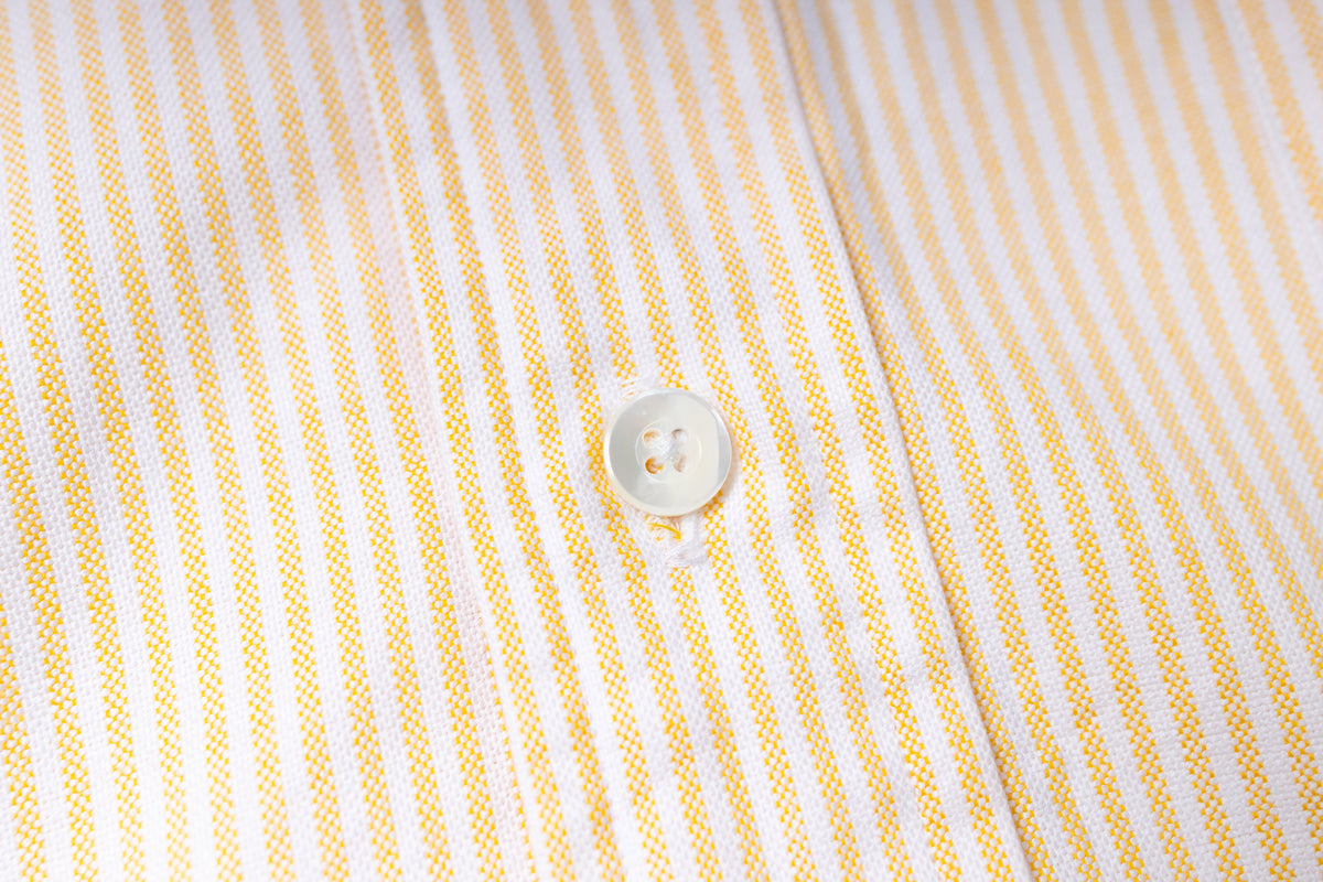 Close-up of a button on a striped fabric shirt