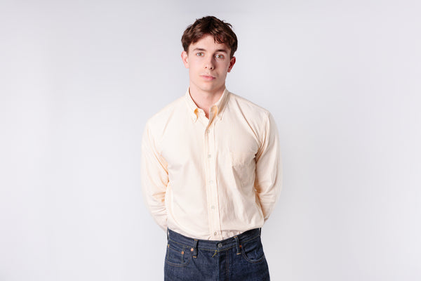 A man wearing a yellow stripe oxford shirt on a white background