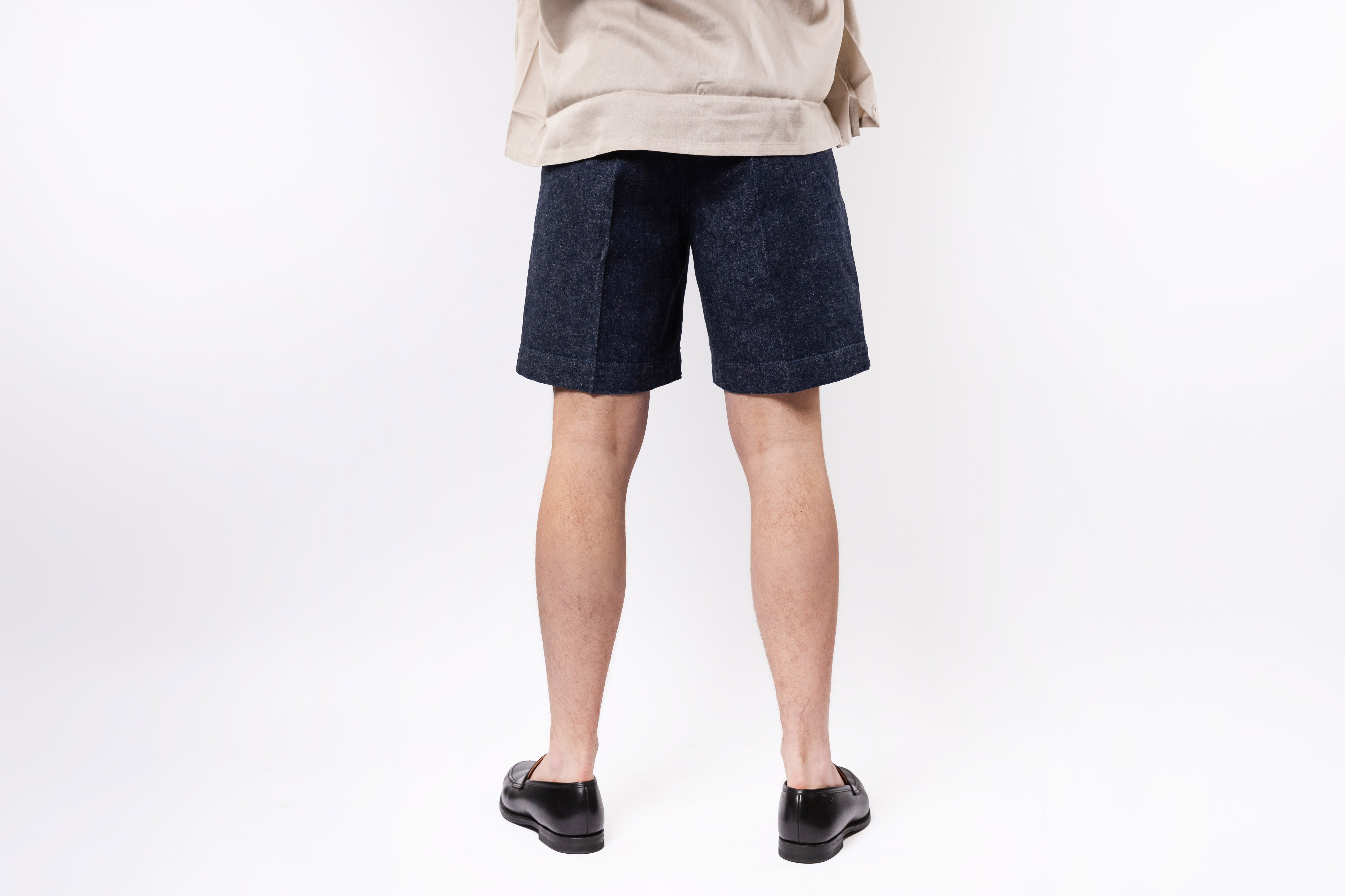 Person wearing dark denim shorts on a white background