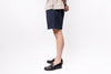 Person wearing dark denim shorts and black shoes on a white background