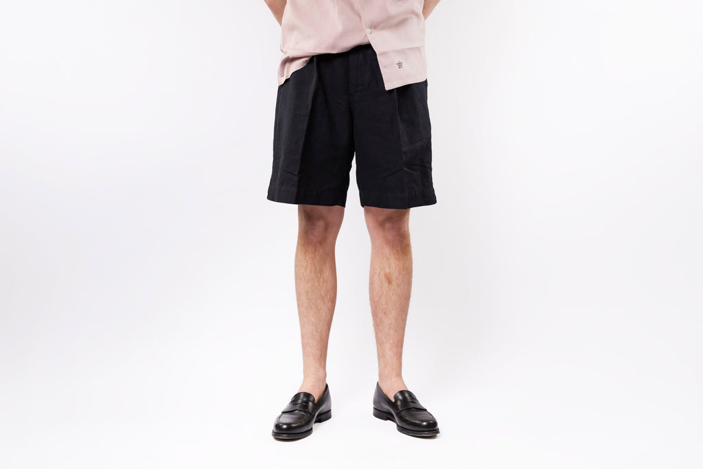 Person wearing black shorts and a light-colored shirt on a white background