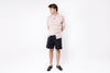 Person wearing a light pink shirt and black shorts on a white background