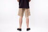 Person wearing beige shorts and black shoes on a white background
