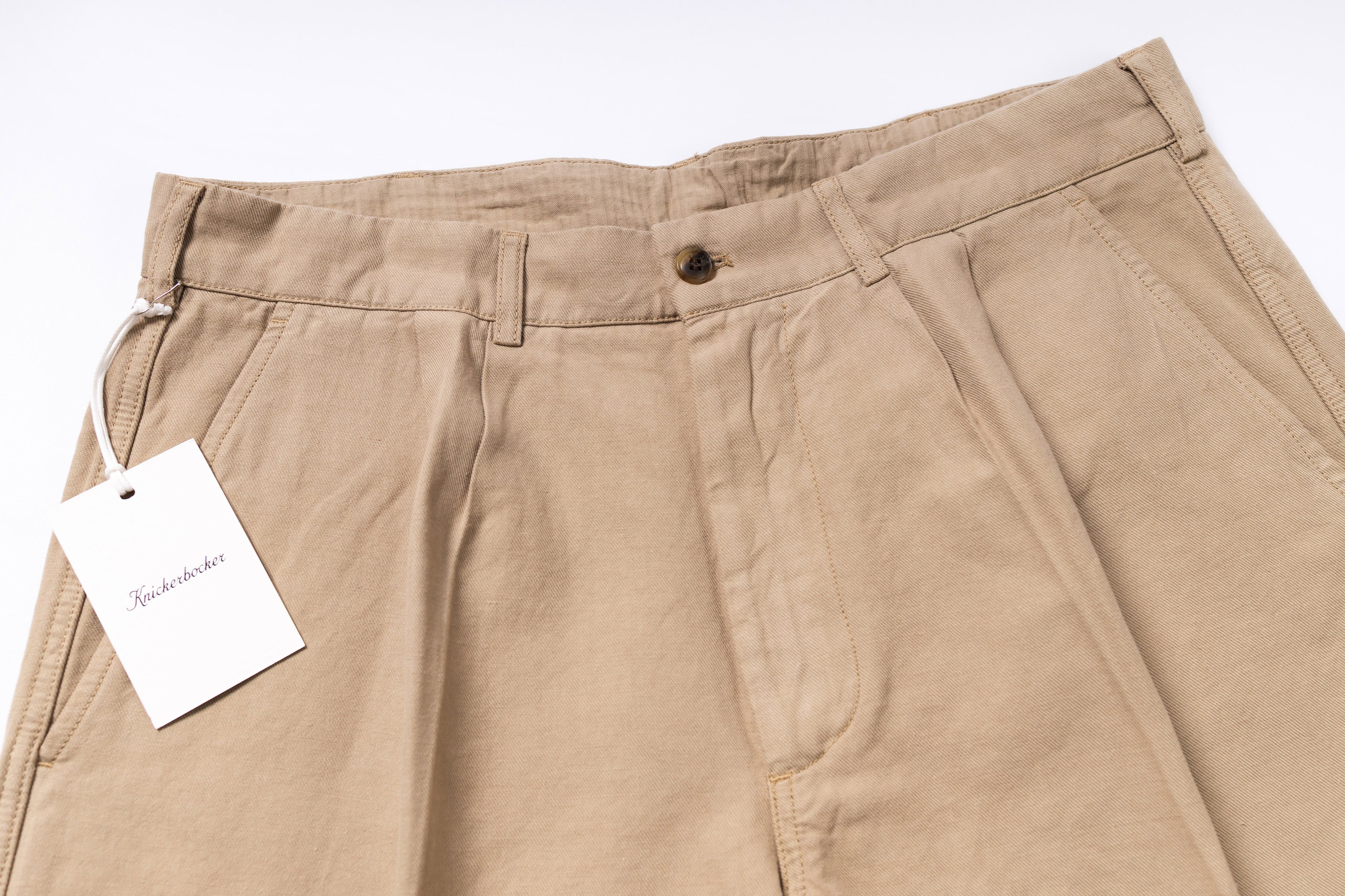 Beige pants with a tag on a white background