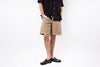 Person wearing beige shorts and black shoes on a white background