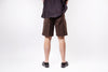 Person wearing brown shorts and black shoes on a white background
