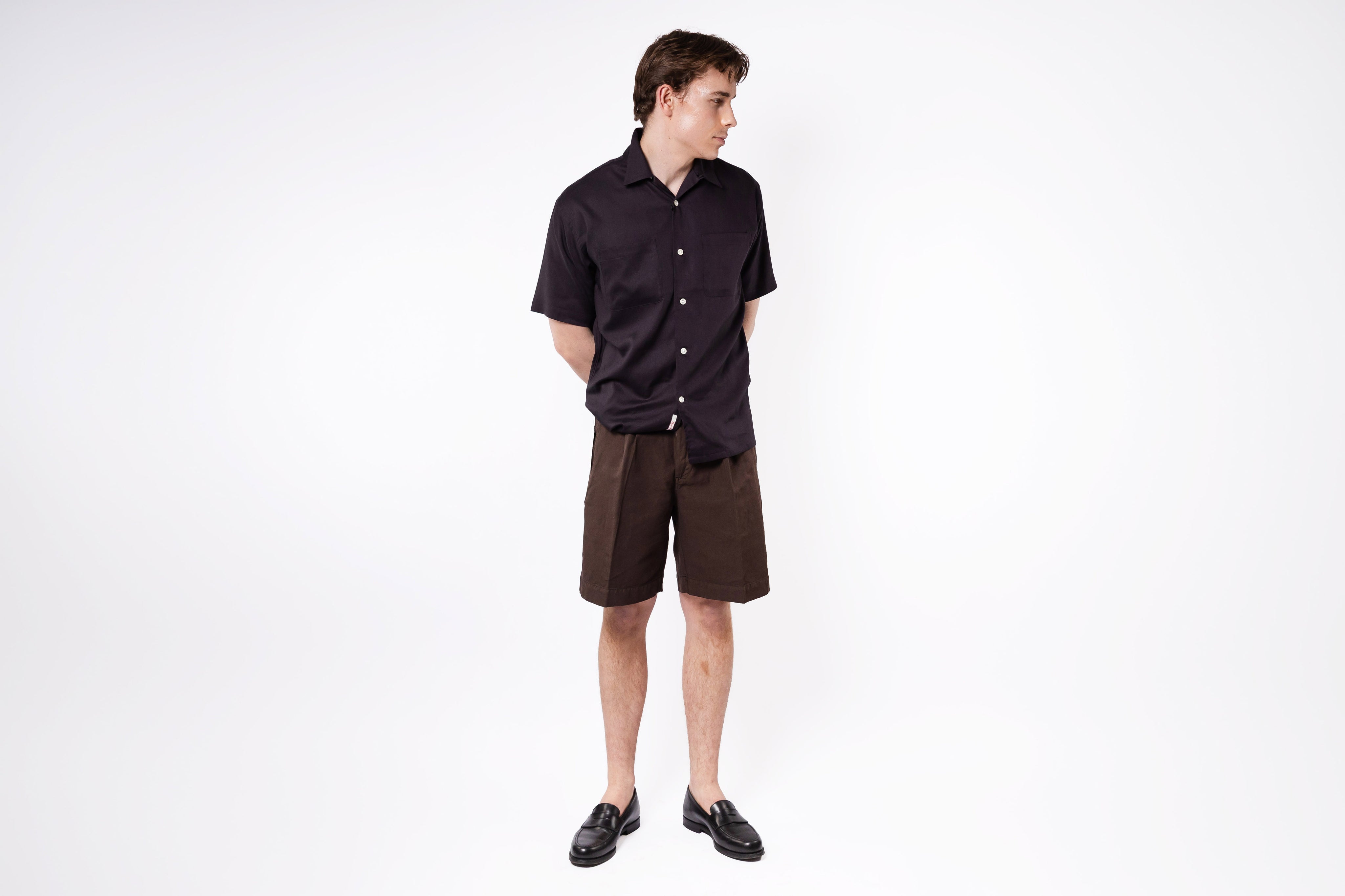 Man wearing a black shirt and brown shorts on a white background