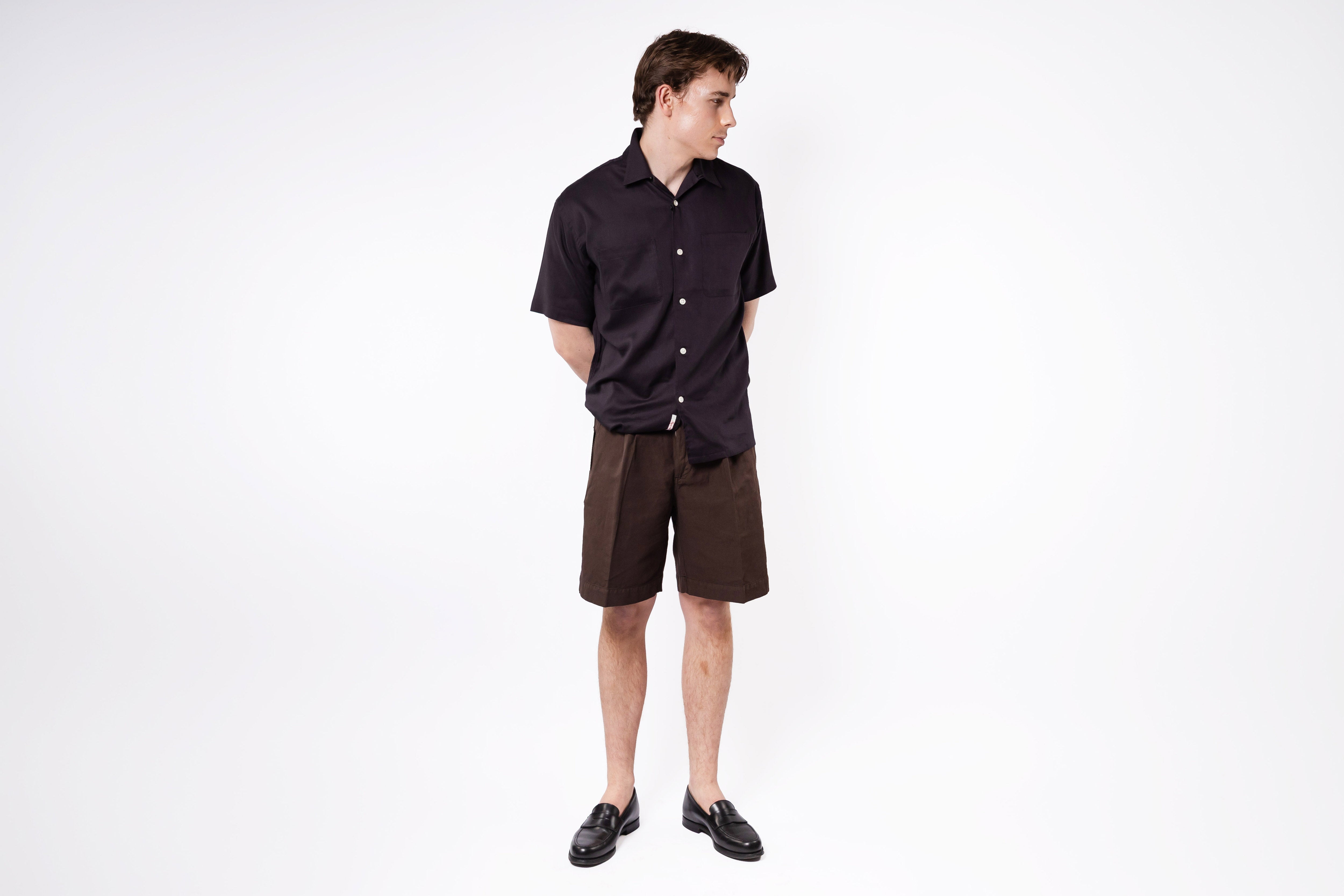 Man wearing a black shirt and brown shorts on a white background