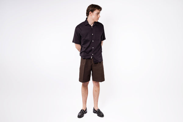 Man wearing a black shirt and brown shorts on a white background