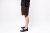 Person wearing brown shorts and black shoes on a white background