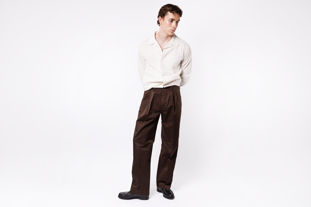 Man wearing a white shirt and brown pants on a white background